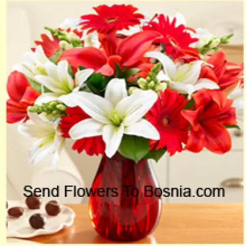 Gerberas rojas, lirios blancos, lirios rojos y otras flores variadas dispuestas hermosamente en un jarrón de vidrio