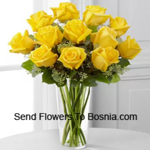 12 roses jaunes avec quelques fougères dans un vase en verre