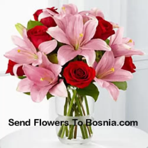 Roses rouges et lys roses avec des remplissages saisonniers dans un vase en verre